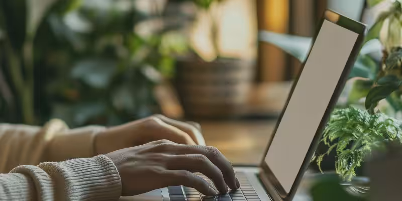 Mains sur un ordinateur portable au milieu de plantes vertes